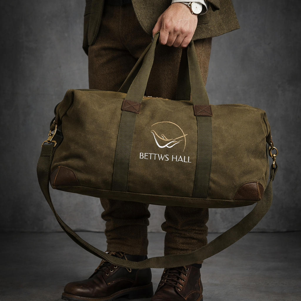 Person holding a green duffel bag with 'Bettws Hall' logo against a dark background